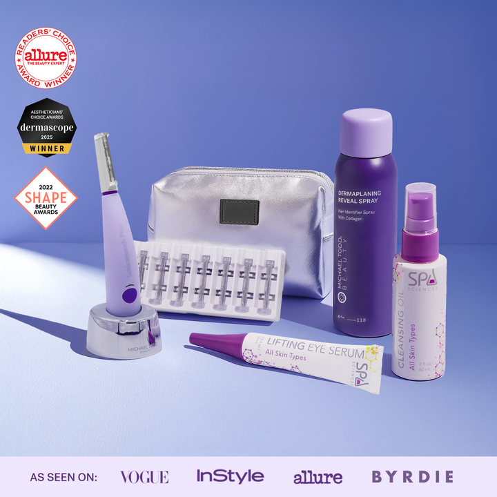 The Michael Todd Beauty Sonicsmooth Starter System, with eye serum, cleansing oil, spray, pouch, and accessory case—plus award badges—is beautifully displayed on a purple surface.