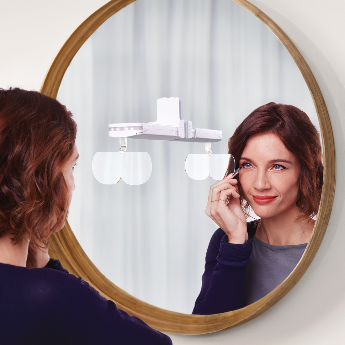 A woman is checking her reflection in a mirror during a grooming session with the Younilook Cosmetic Readers from Michael Todd Beauty.