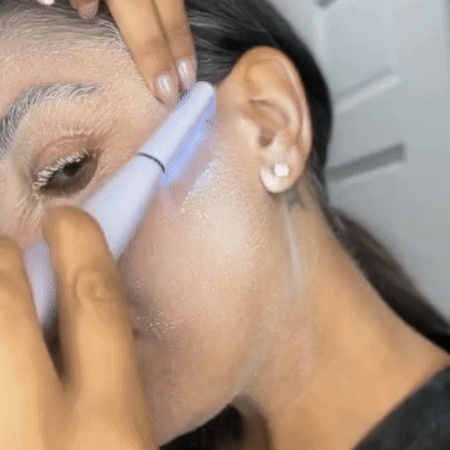 A person using an electric facial cleansing brush on their cheek.